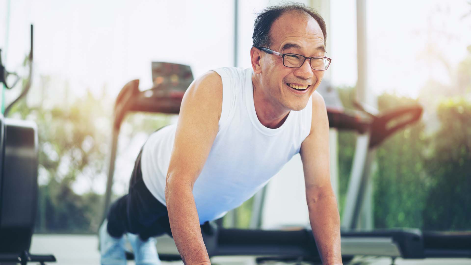 An older man doing a push-up in a gym environment