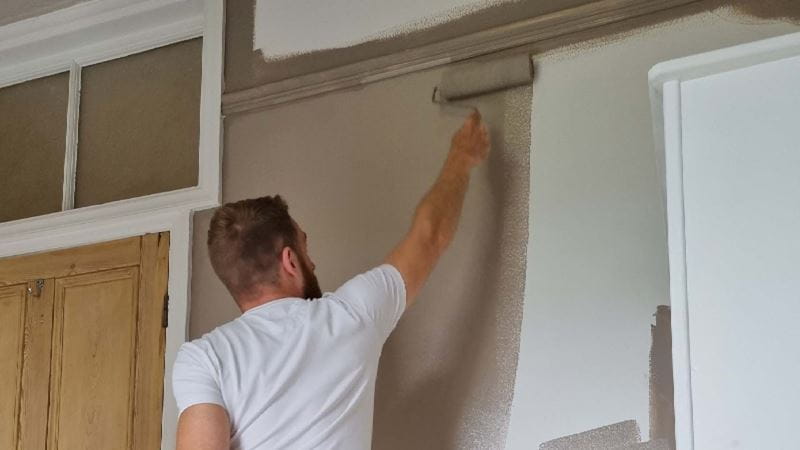 Man painting walls with a painting roller