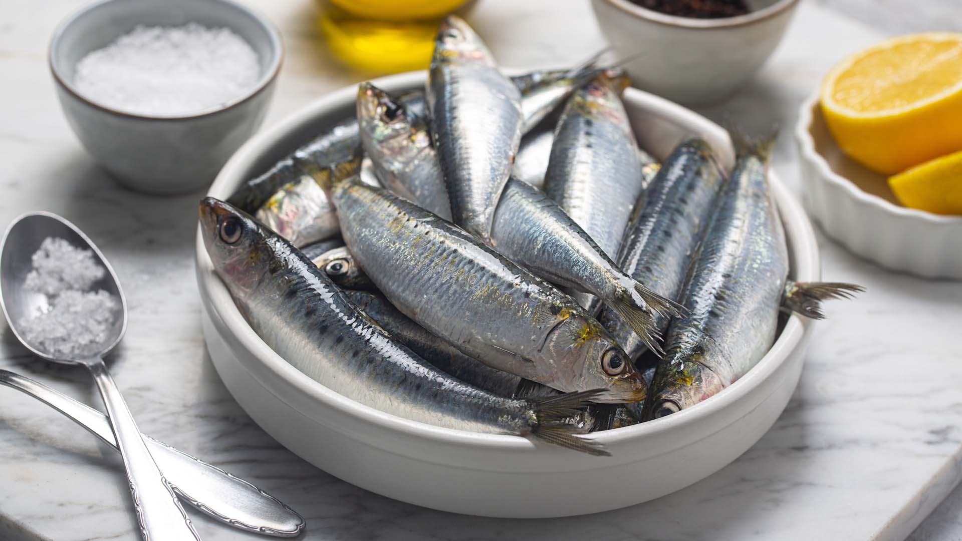 Fresh sardines, lemon and salt on kitchen worktop