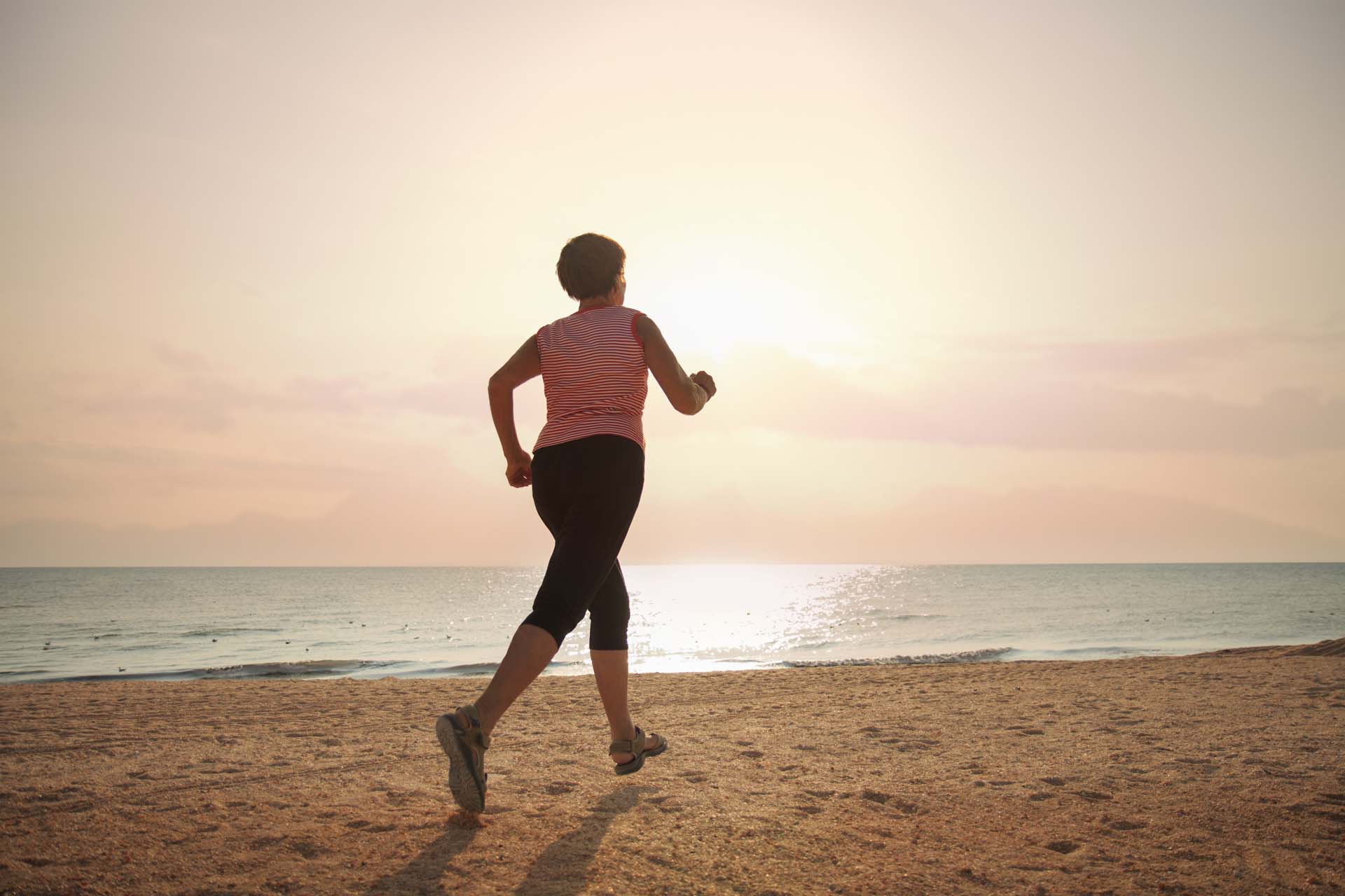 A woman running along the beach as the sun comes up