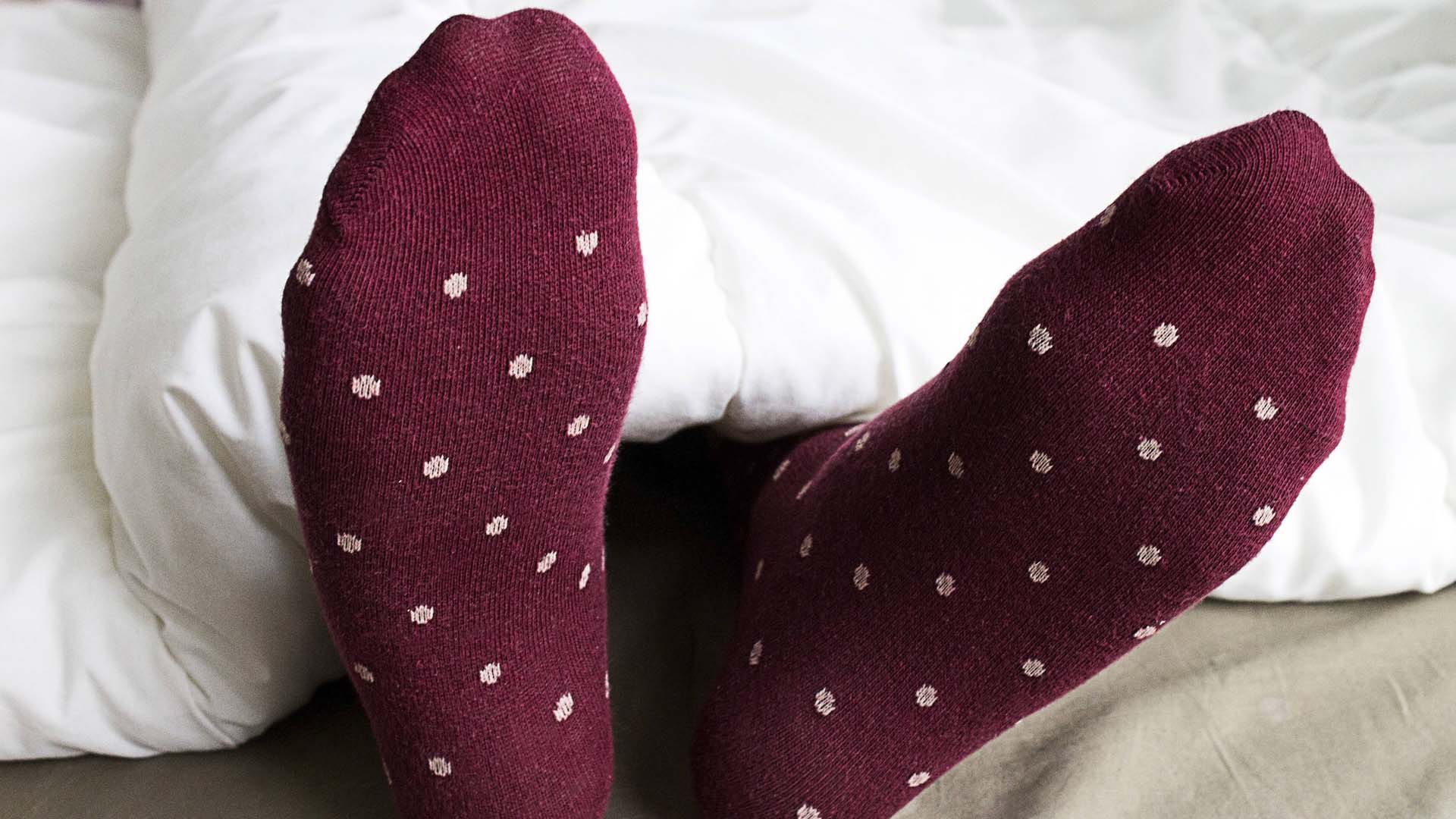 Someone lying in bed with a pair of spotty socks on