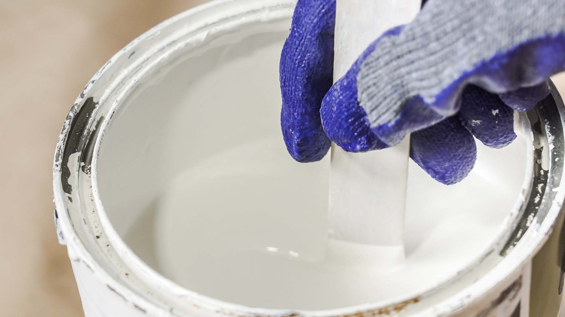 stirring white paint with a blue hand