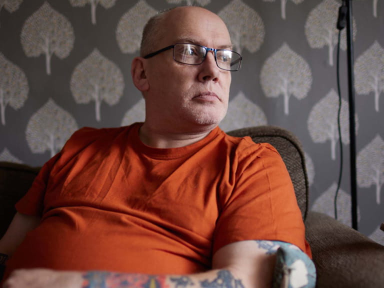 Tom Middlemass wearing glasses and an orange T-Shirt looking out a window