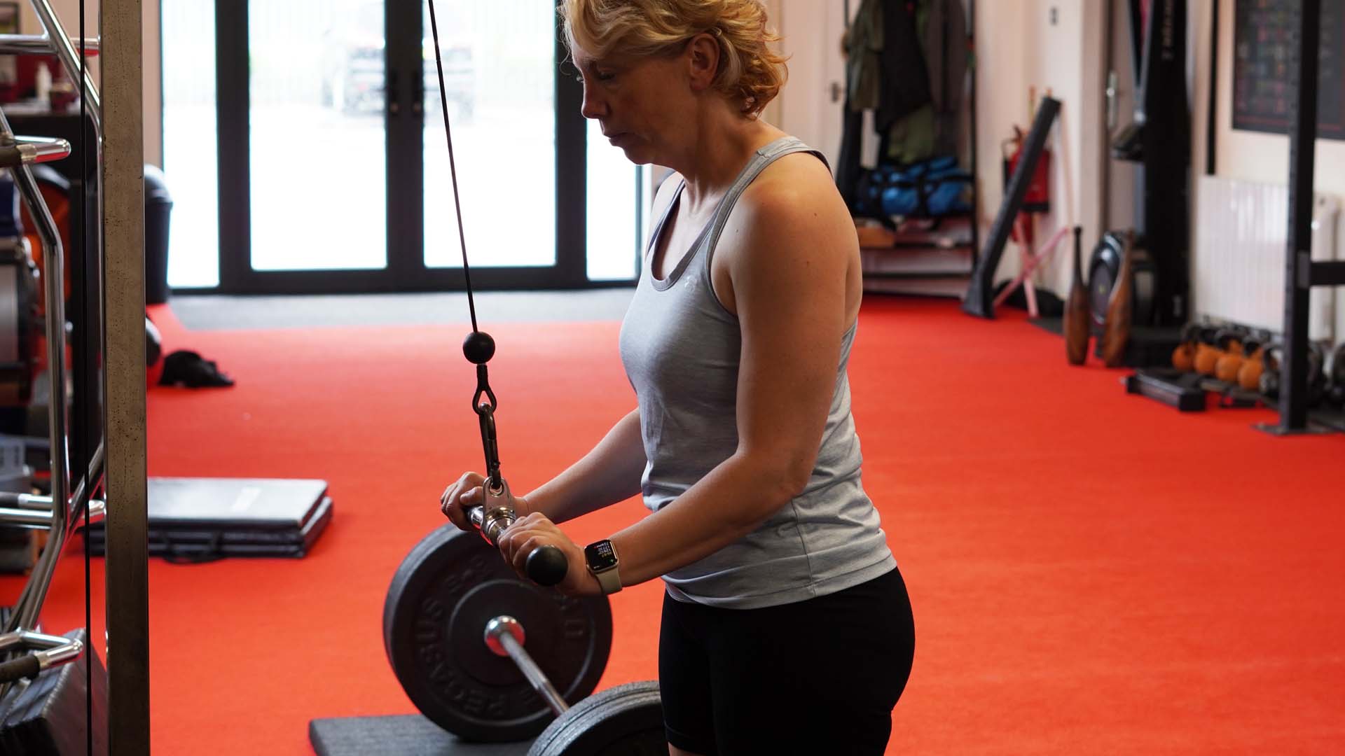 A woman in a gym using a weights machine