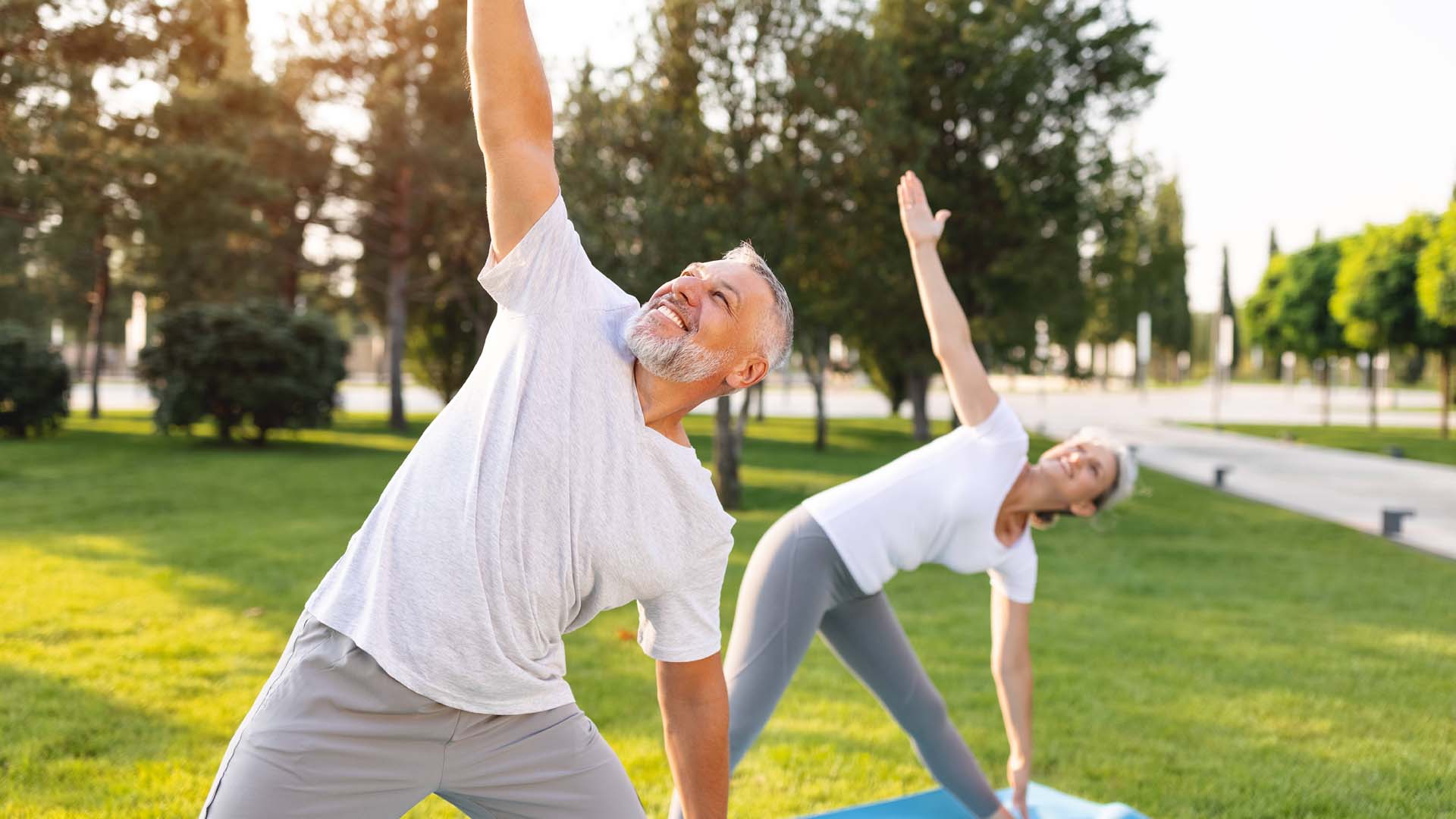 A man and woman doing yoga triangle pose.