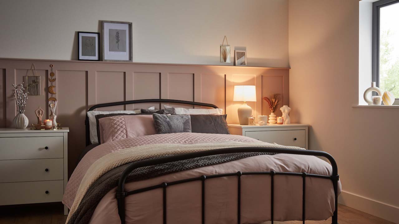 pale pink panelling half way up the wall with a bed in front