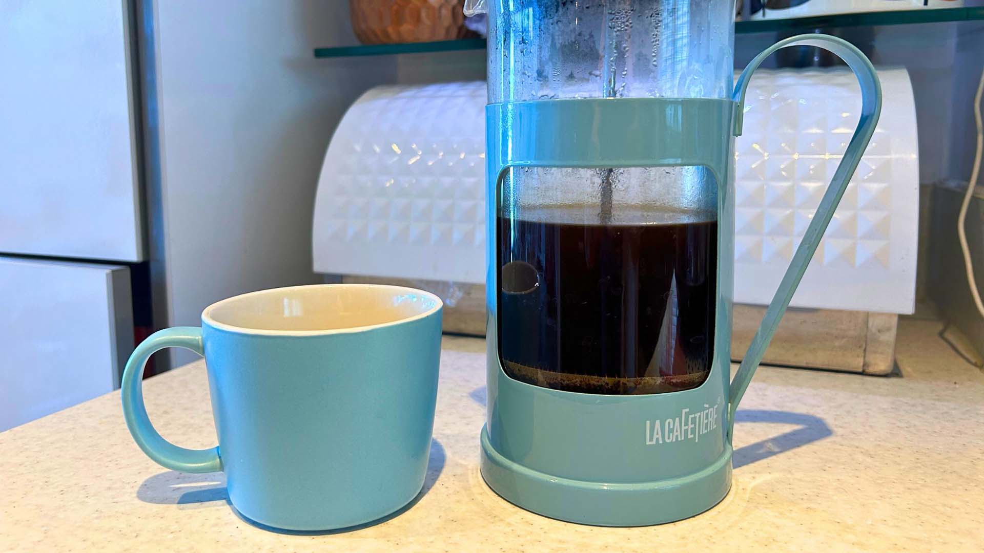 A coffee cup next to a cafetiere
