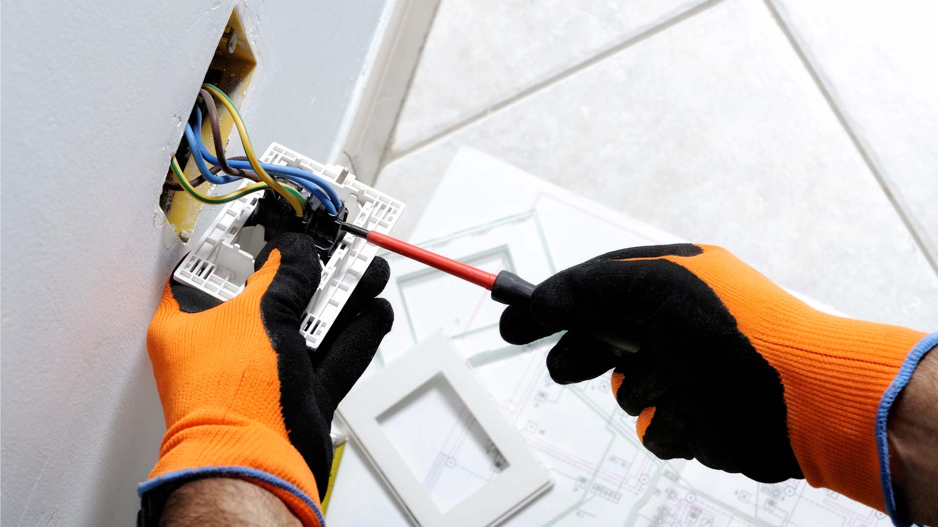 A person wearing gloves working on the electrics of a socket