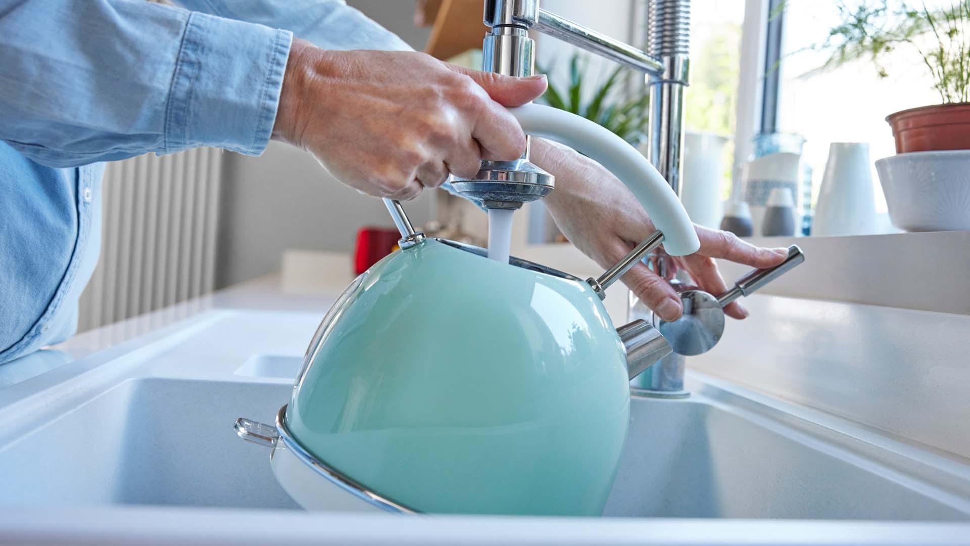 A person filling a kettle from the tap
