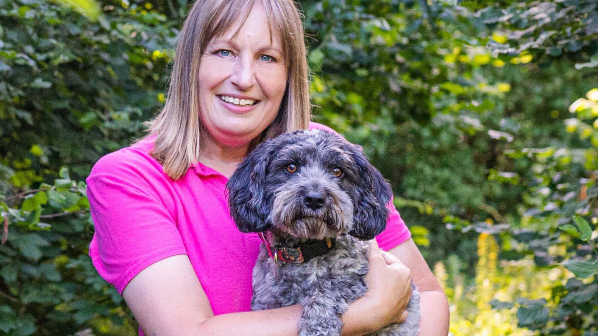 Dog trainer Jo Sellers holding her dog in the garden