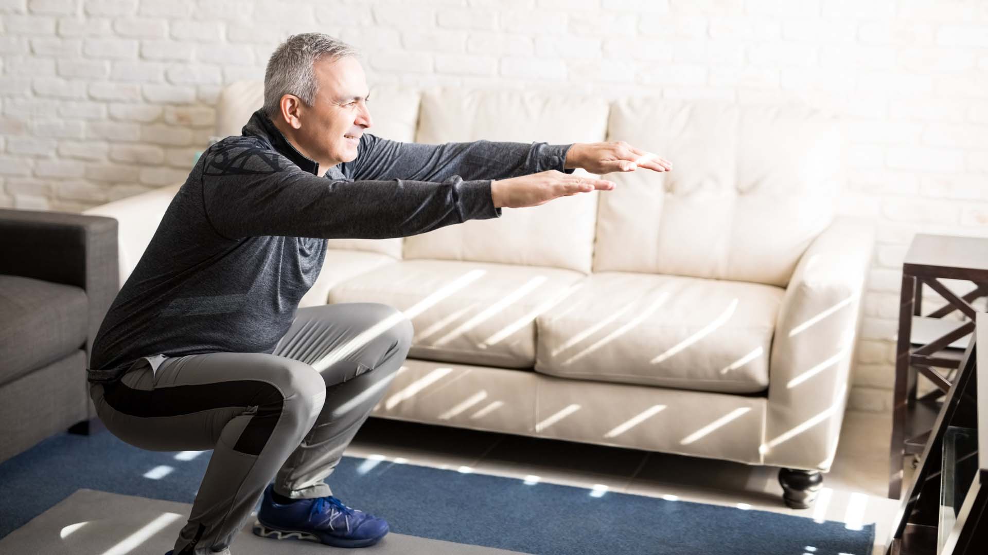 Man doing squats by his sofa