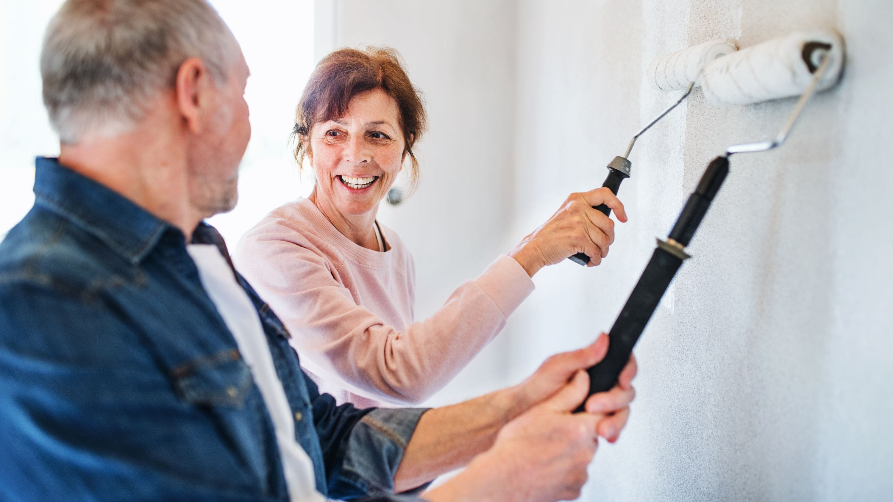 Mature couple painting a wall laughing