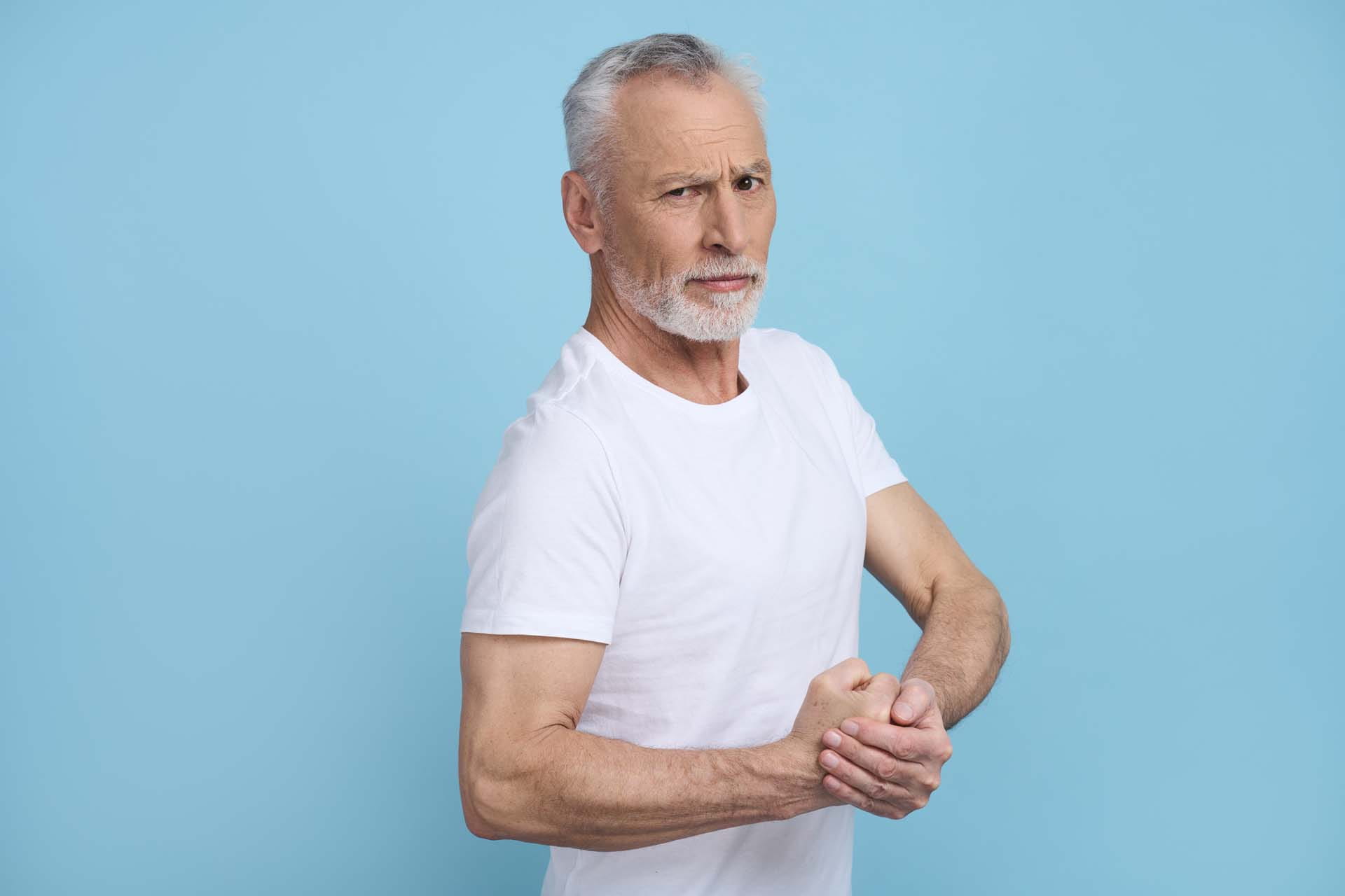 An older man showing off his arm muscles and winking at the camera
