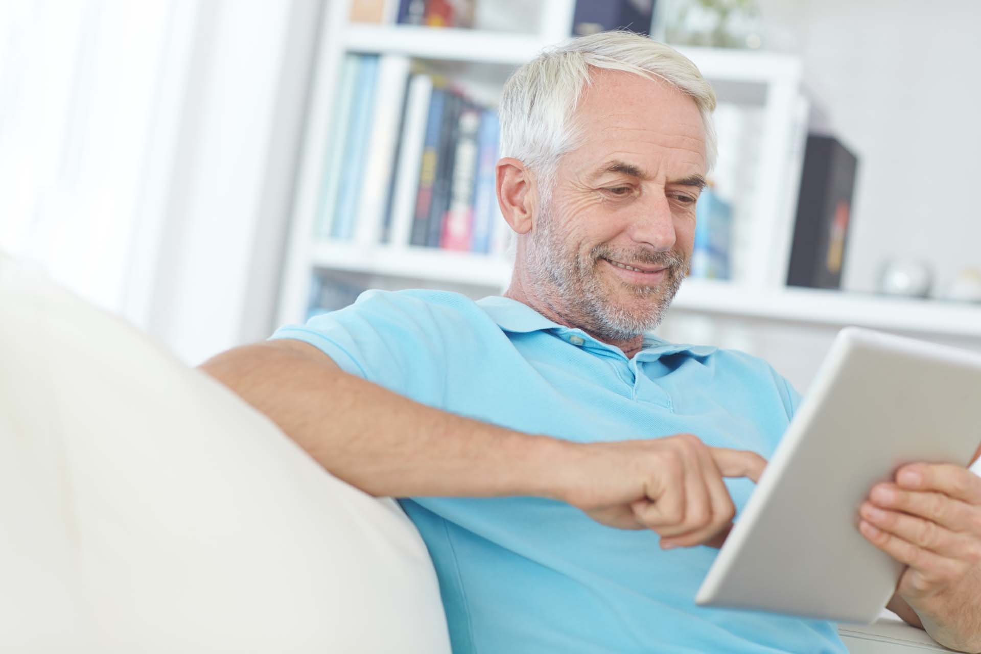 A man in a blue shirt solves puzzles on his tablet