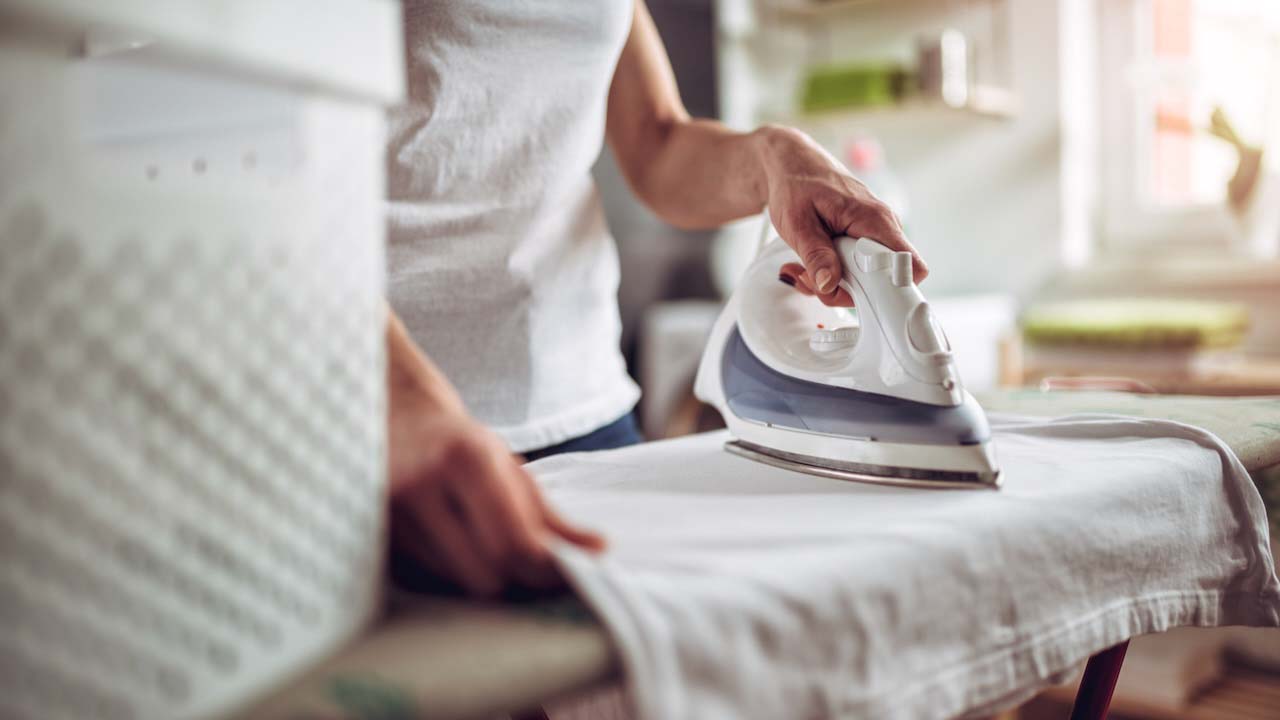 Woman ironing a white tea towel