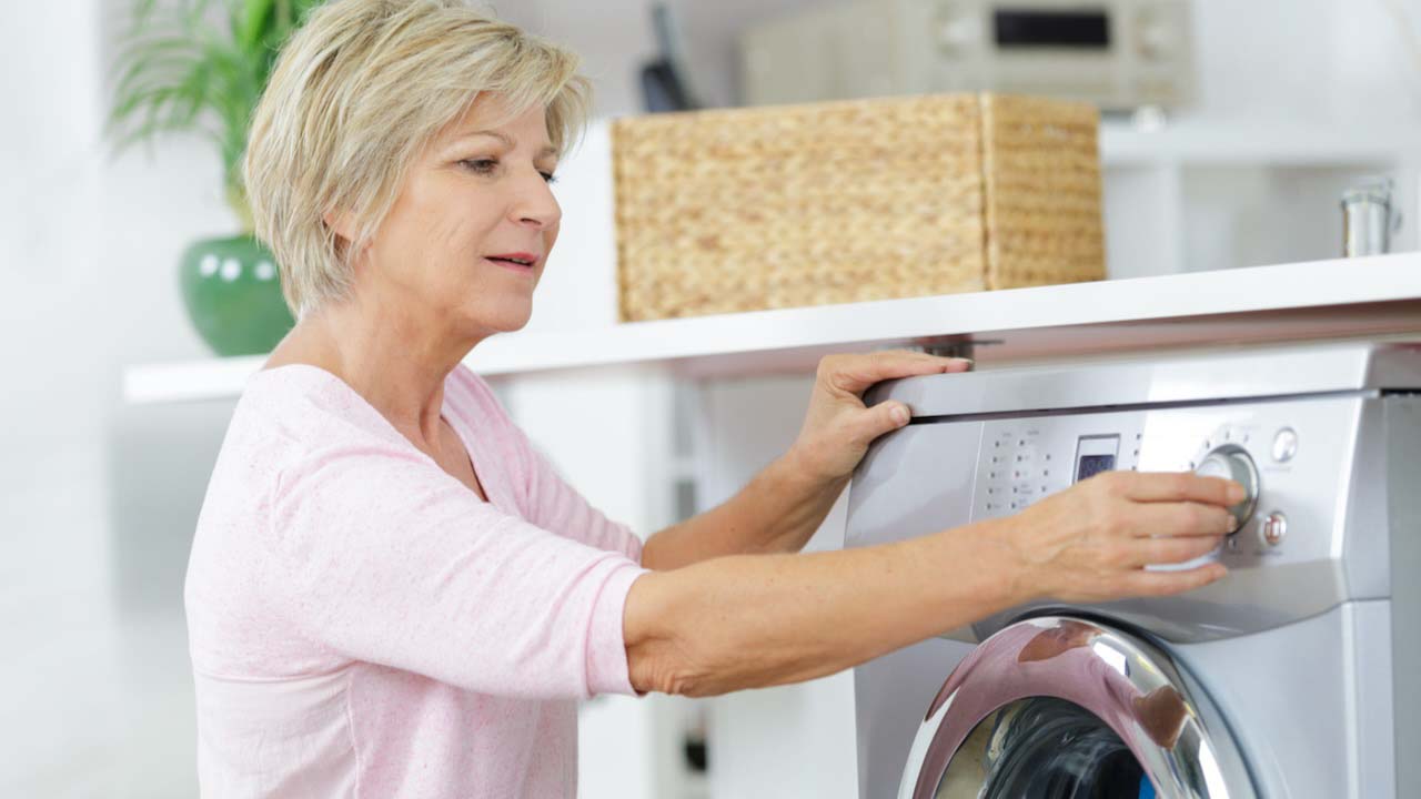 senior woman loading washing machine at home
