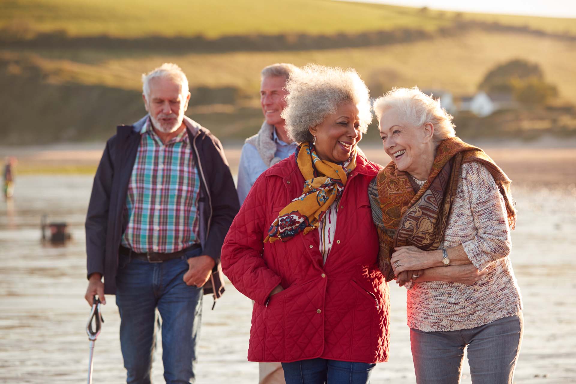 Two smiling older couples walking along a beach