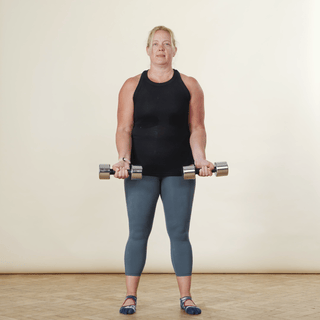 Woman doing a zottman curl with dumbbells, curling the weights up, turning and pushing down
