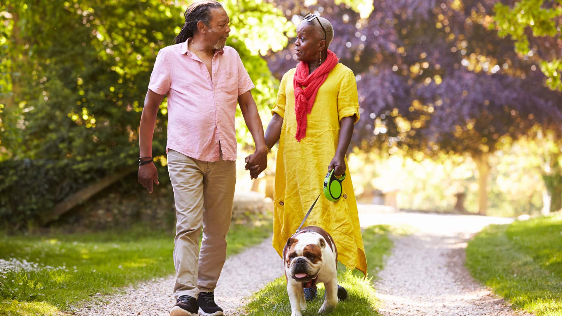 Man and woman walk dog in park