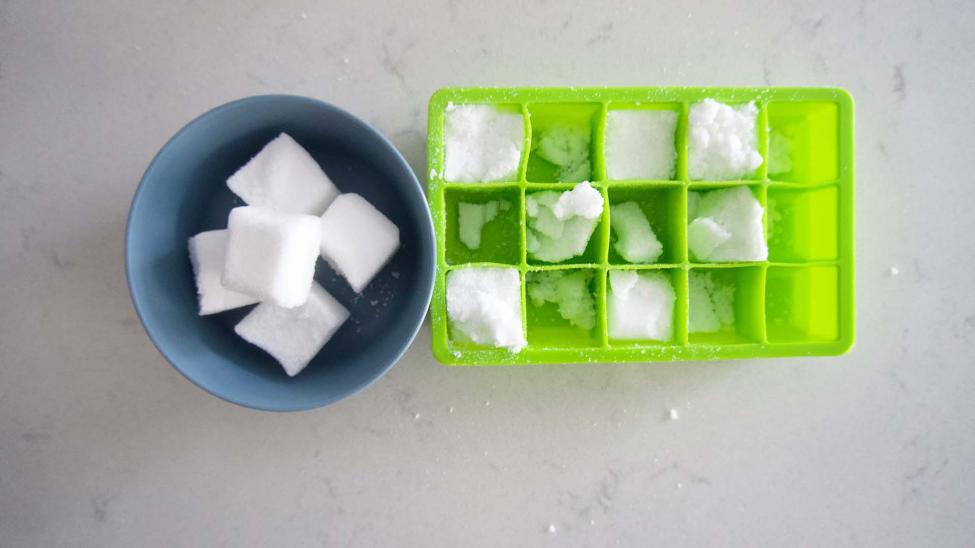 A bowl full of toilet bomb cubes next to a partially emptied ice cube tray