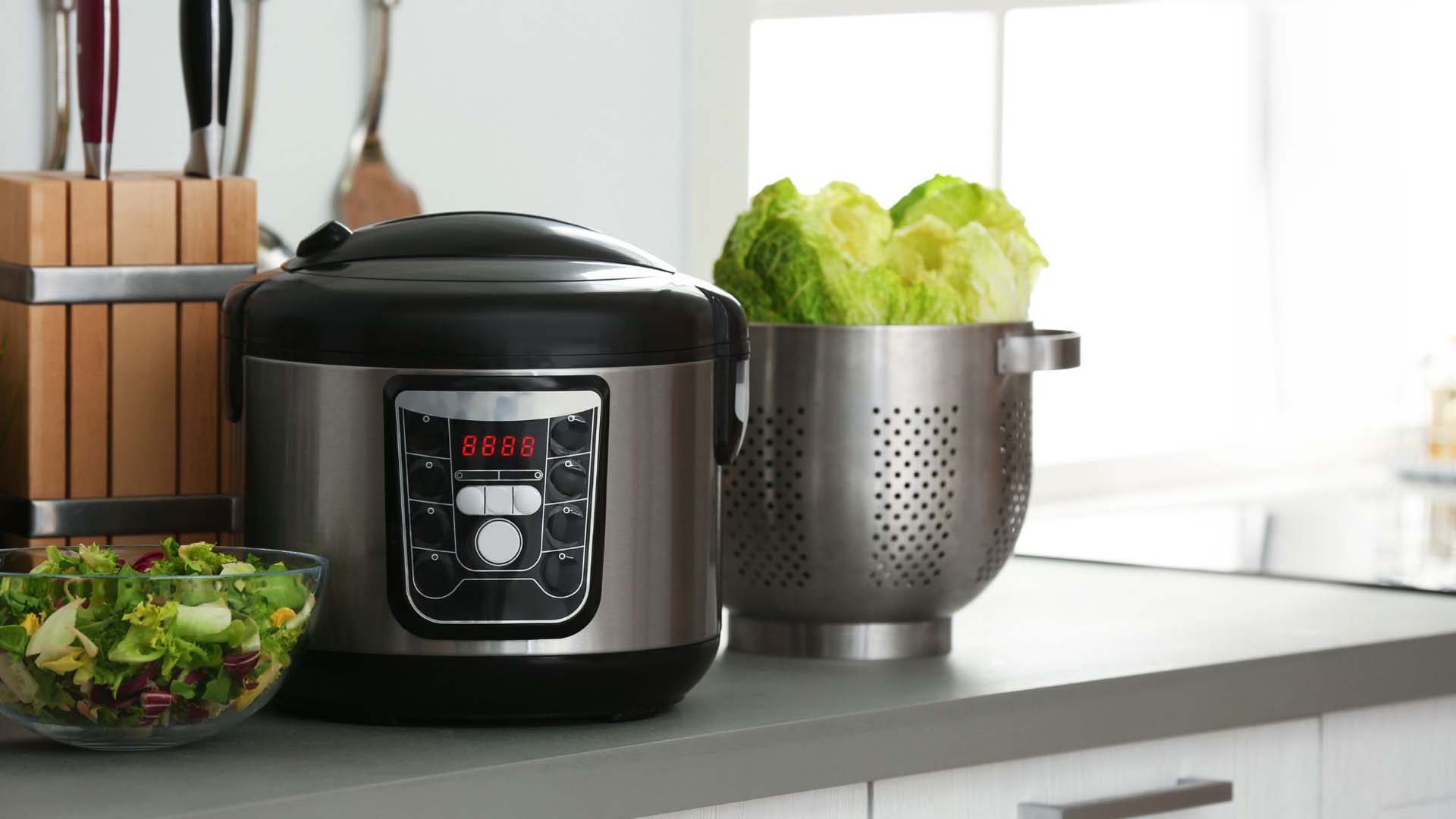 A pressure ccooker on a kitchen counter next to some vegetables