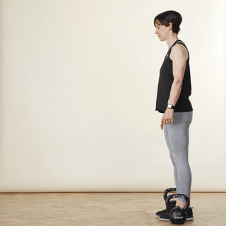 Woman walking and carrying two kettlebells