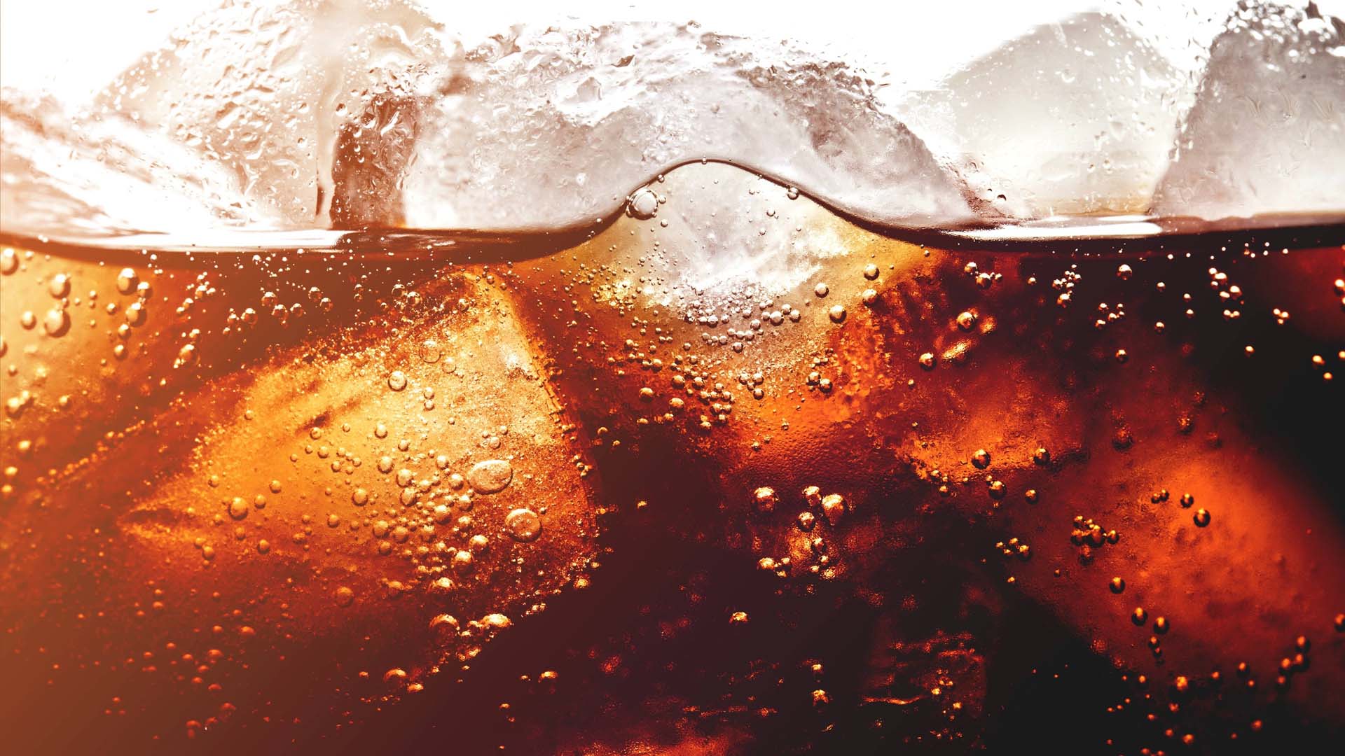 A close up of coca cola drink with ice in it