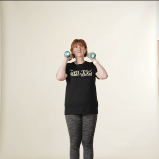 A woman in sports clothing demonstrating an overhead shoulder press with hand weights