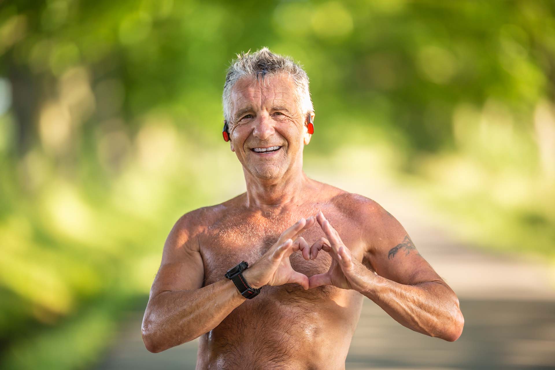 very happy topless man on a run holding his hands to his heart in a heart shape