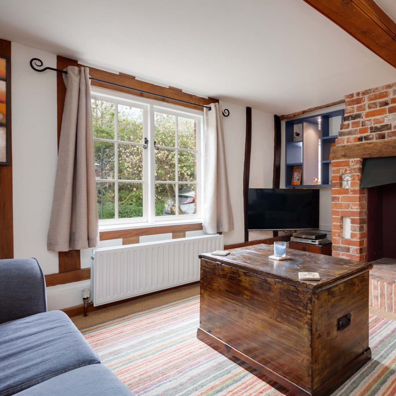 Clare, Suffolk - 27 April 2018: Beautiful charming small traditional cottage living room with inglenook style fireplace and chimney breast with exposed brickwork and cast iron wood burning stove