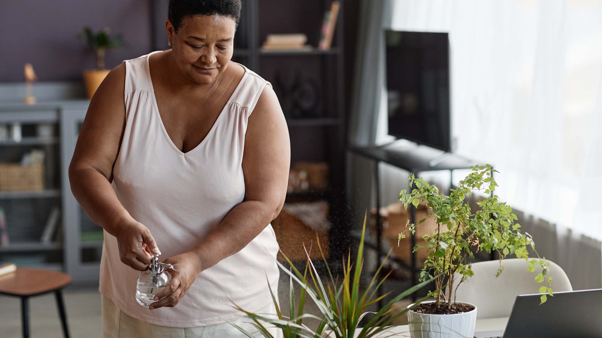 A woman waters her plants with a spray bottle