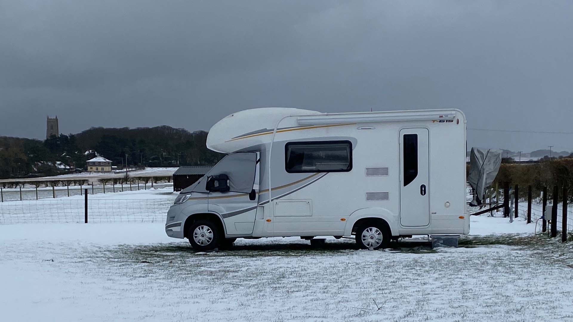 A motorhome covered in snow in a field