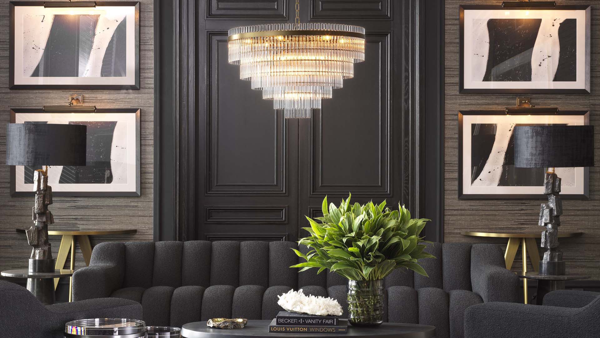 A room with black walls, a black sofa, and a statement crystal chandelier 