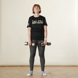 A woman in sports clothing demonstrating an upright row exercise while holding hand weights