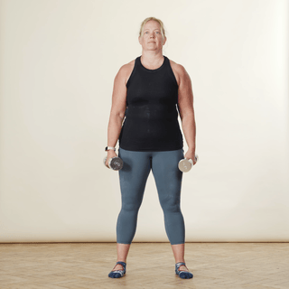 A woman in sports clothing demonstrating a weighted squat