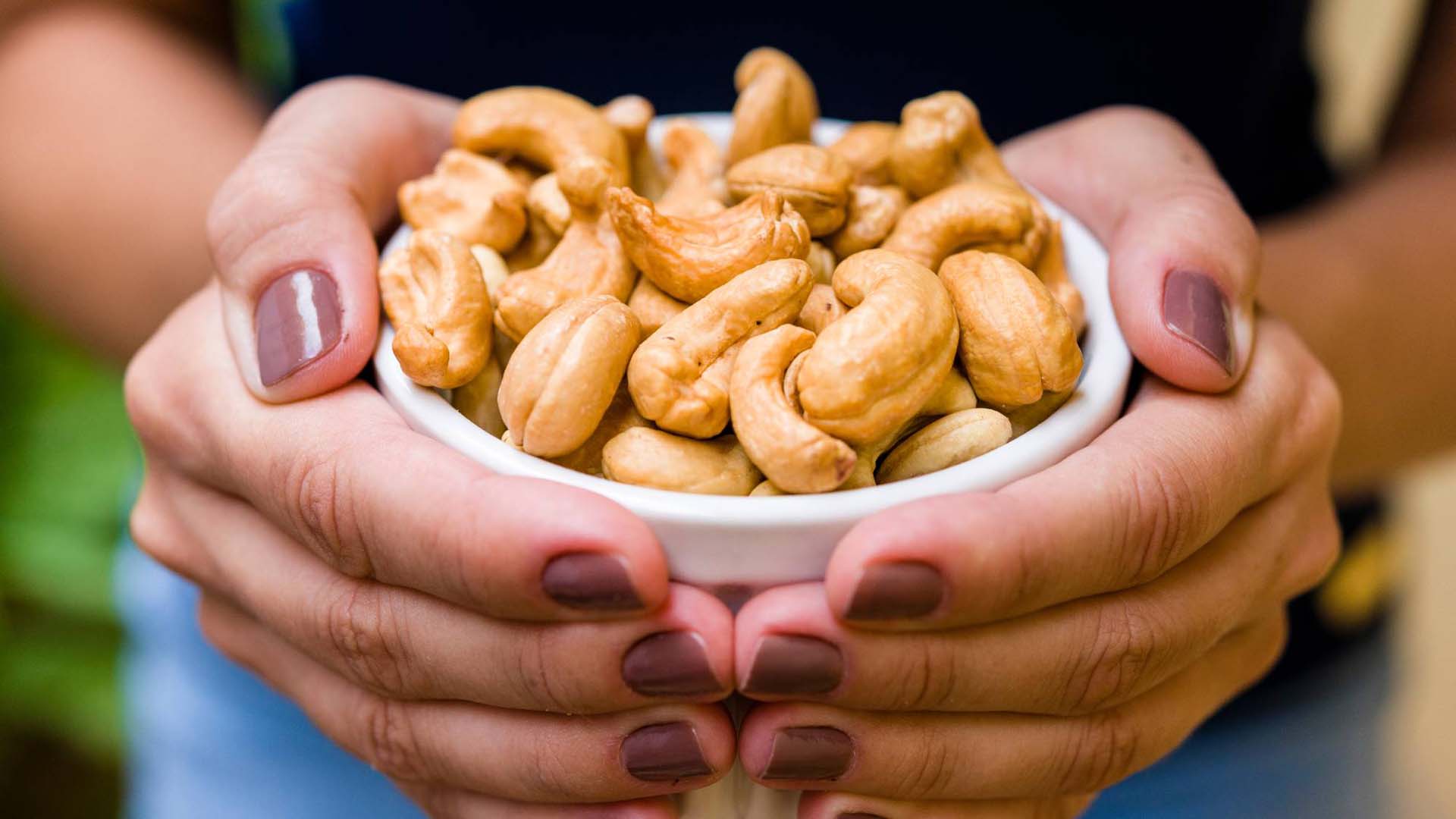 A woman holding a bowl of cashews in both hands