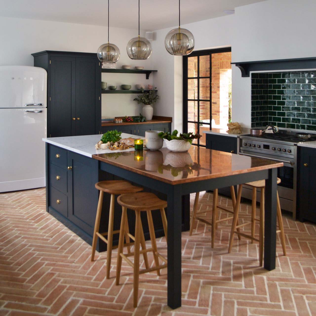 A black deVOL breakfast bar with brick flooring and wooden stools