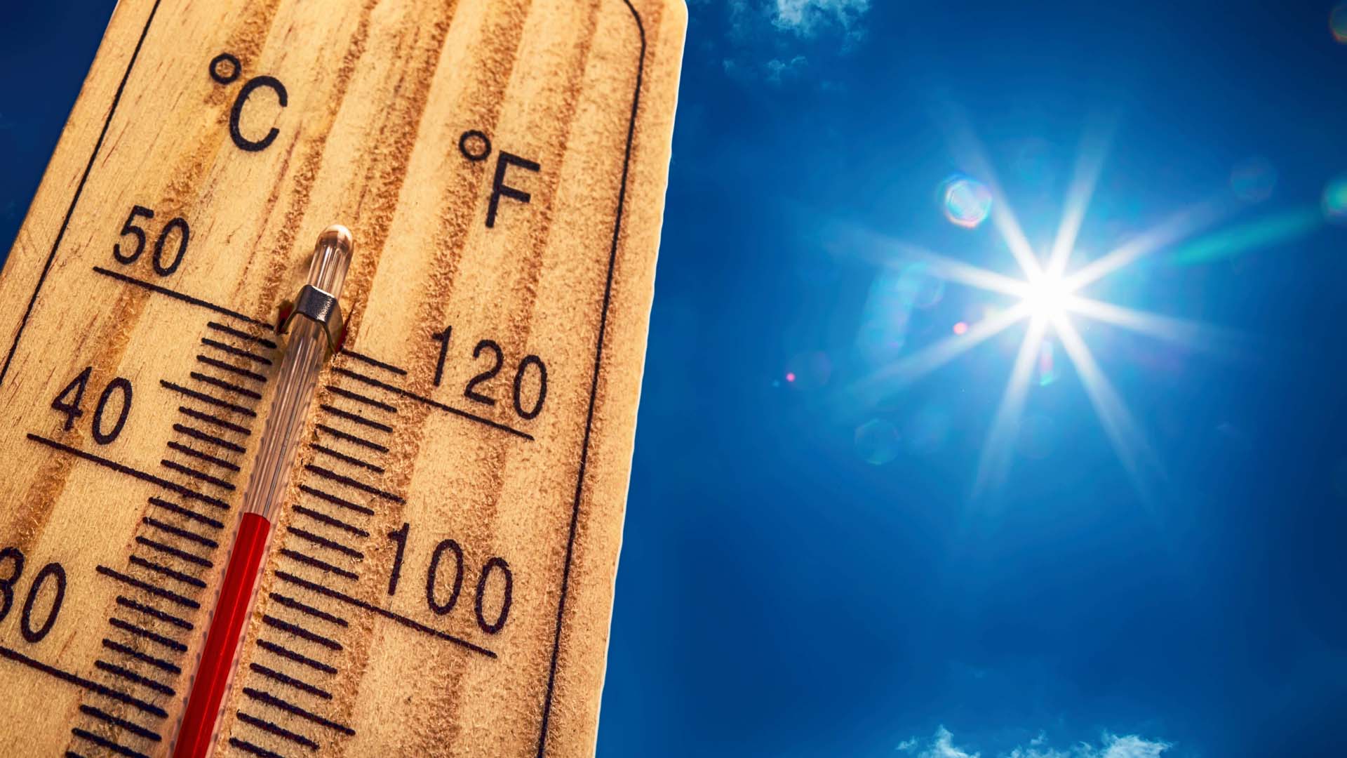 A picture of a thermometer reading 40 degrees celcius, with a blazing sun in the background