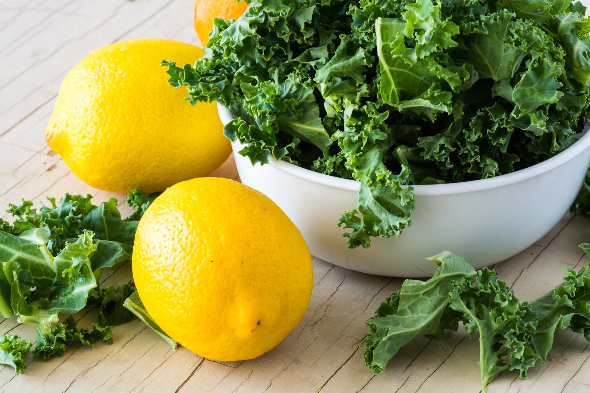 A bowl of kale with some lemons next to it