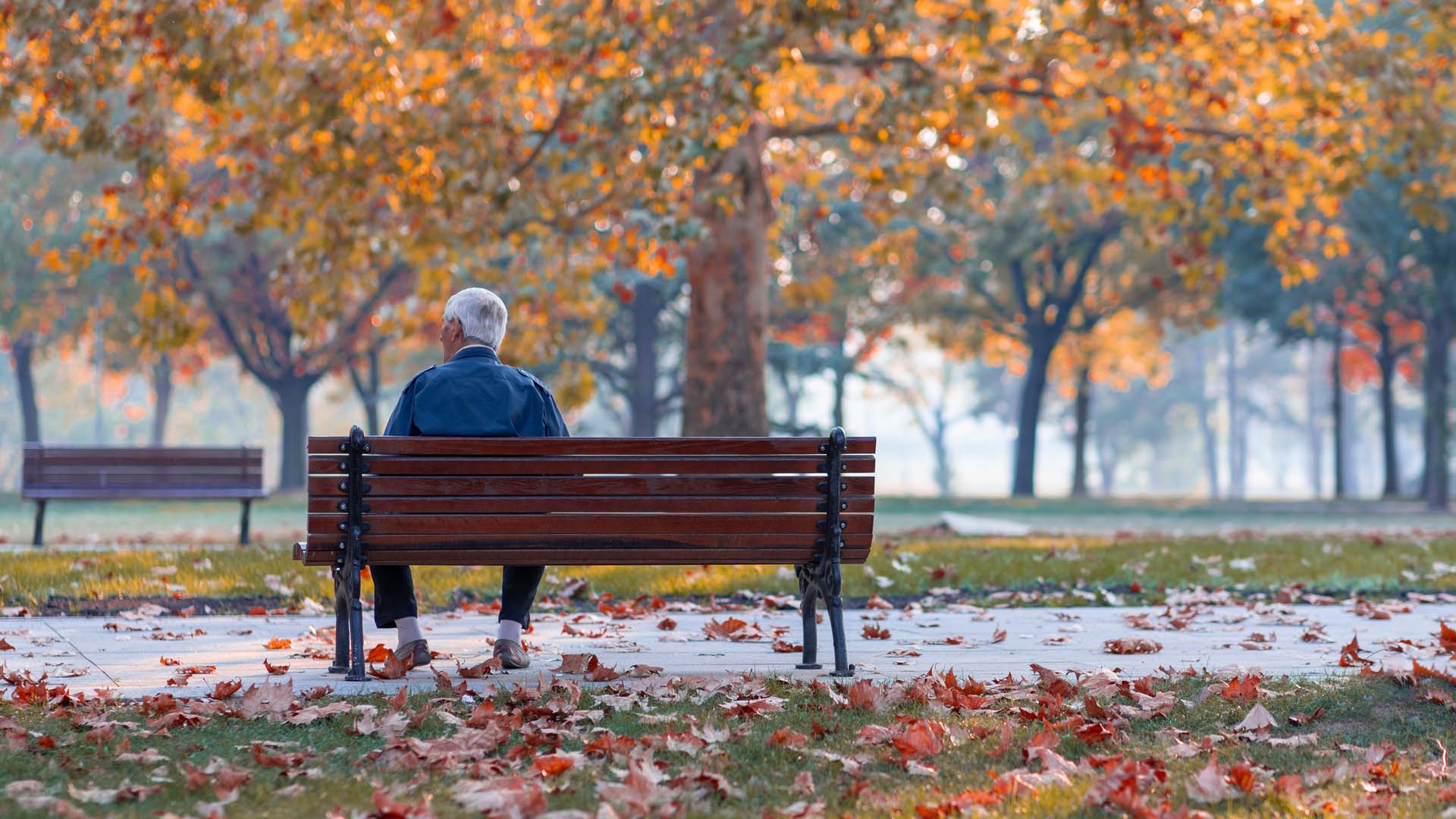 Man sitting on a park bench in autumn