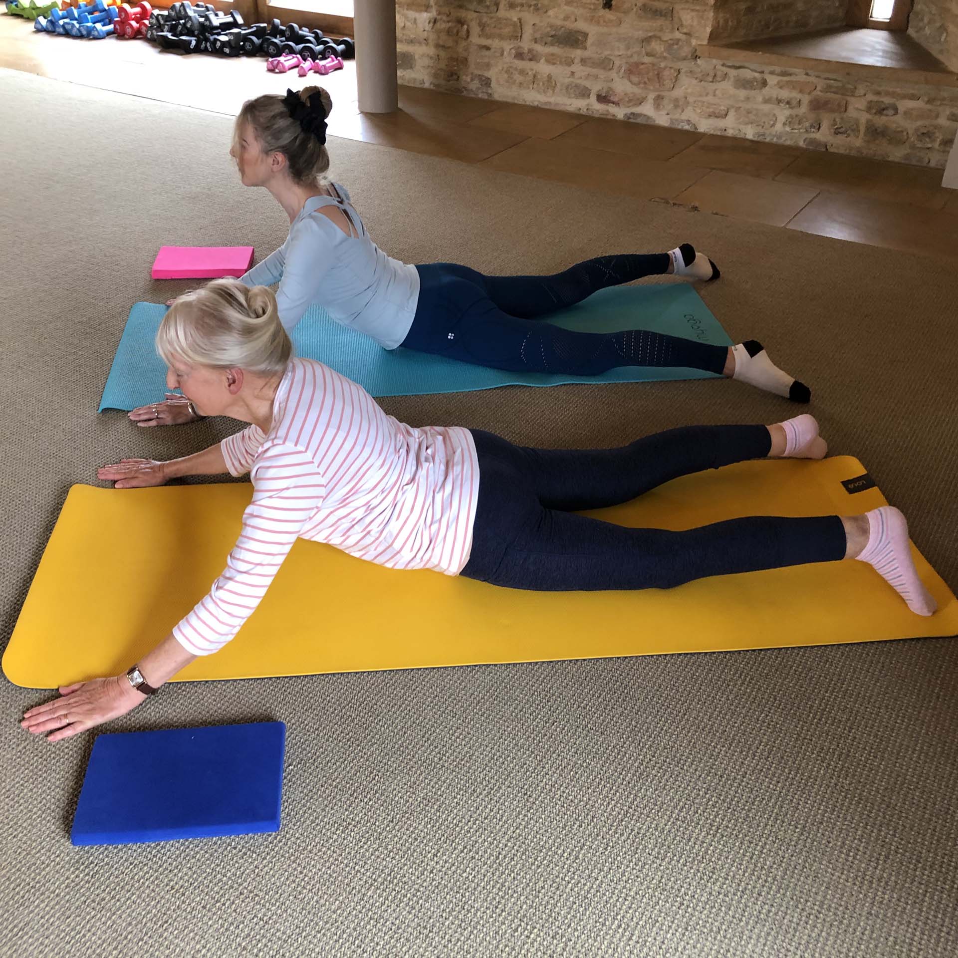 Two older women practising pilates in a studio