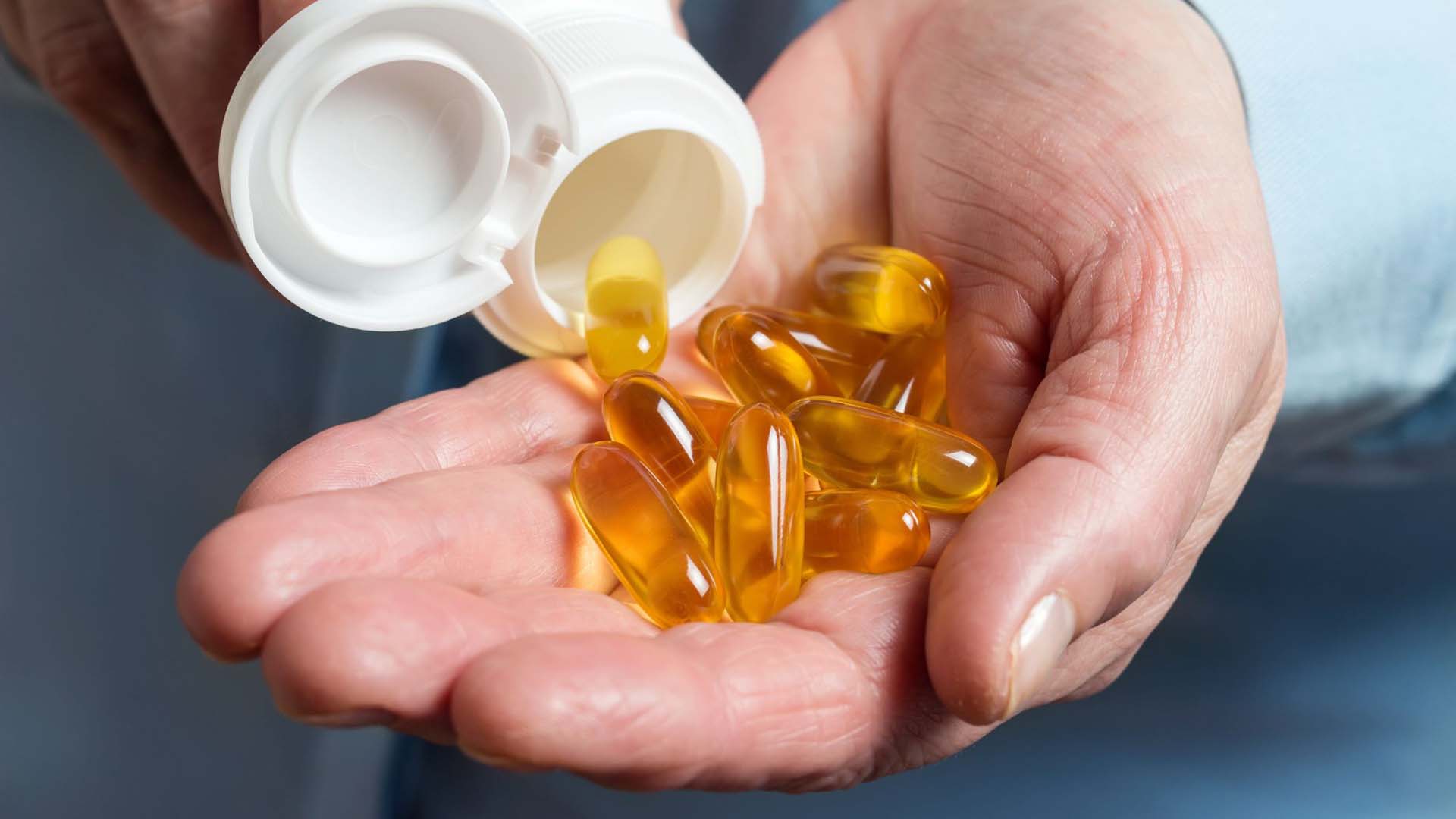 A woman putting Omega 3 supplement capsules into her hand
