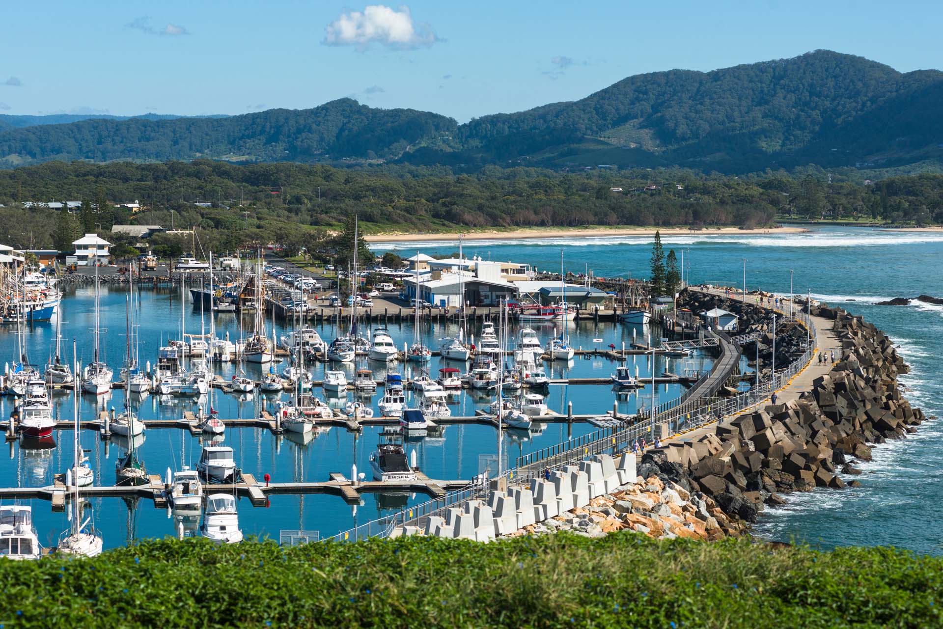 A view over the seaside city of Coff's Harbour, Australia, packed with yachts and pleasure craft with wooded hills in the background.
