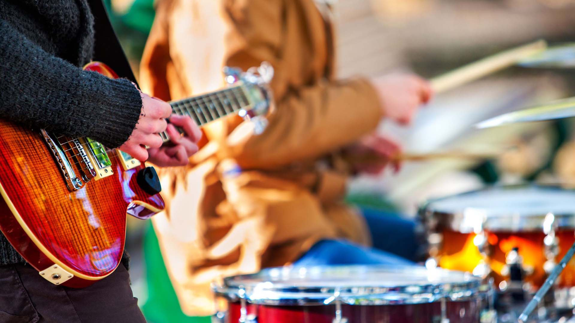 A close-up of a guitarist and drummer playing music