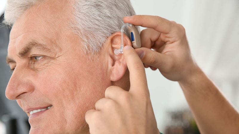 An older man being fitted with a hearing aid