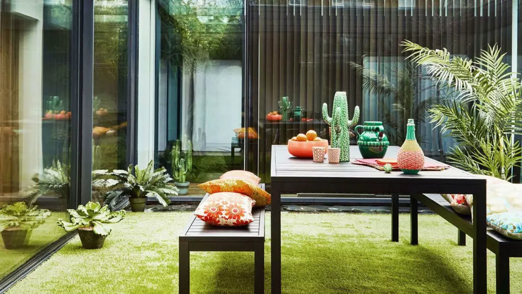 A table and benches with potted plants on artificial grass