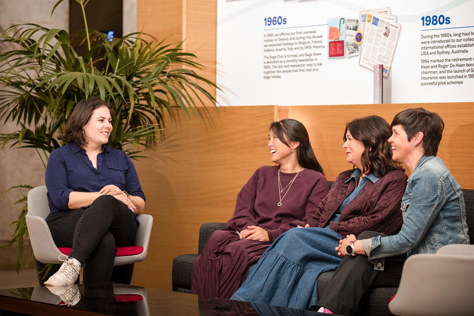 Group seated in a discussion area, listening to a presenter in front of information boards