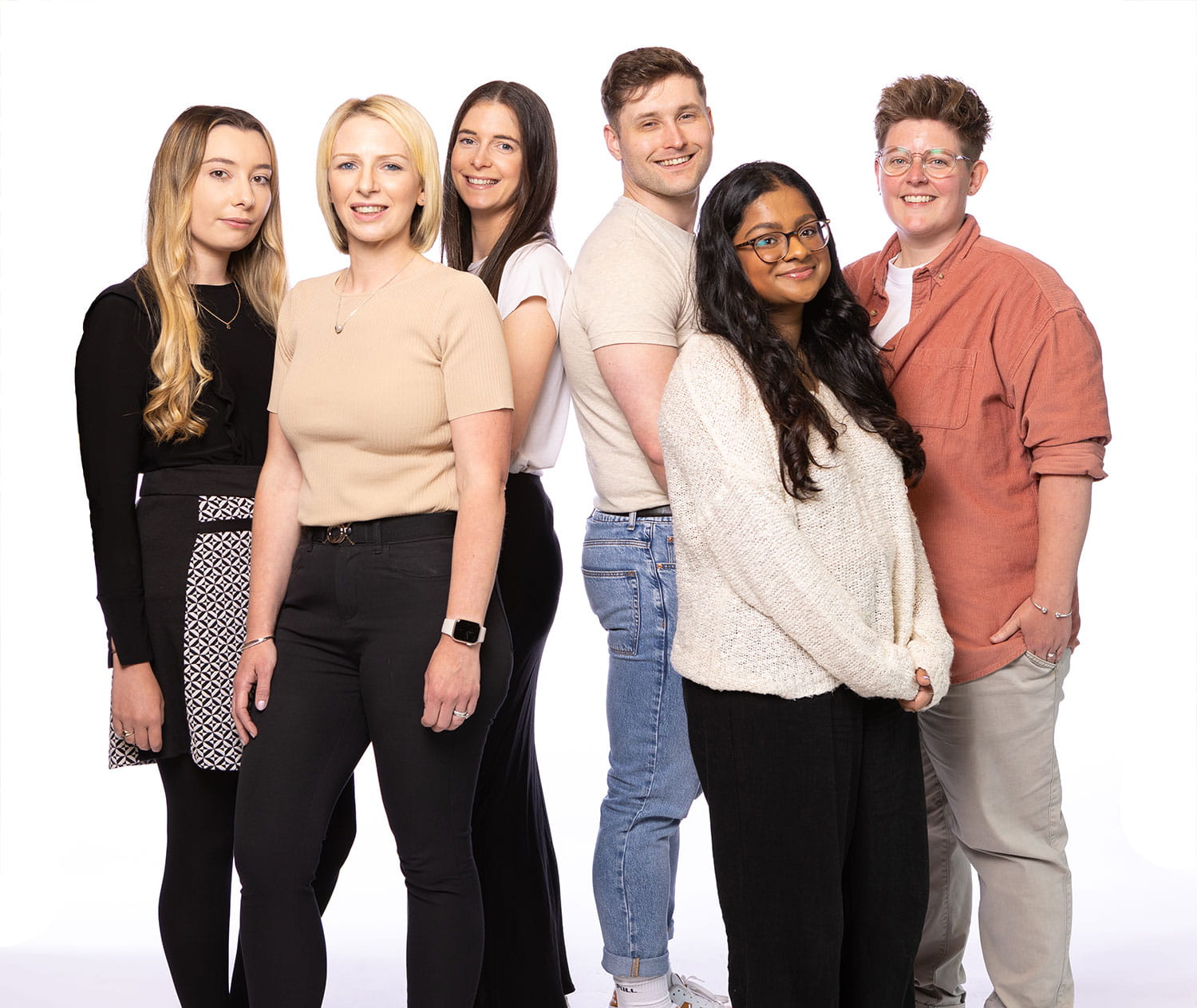 Group of four people walking along a beach with litter picking equipment