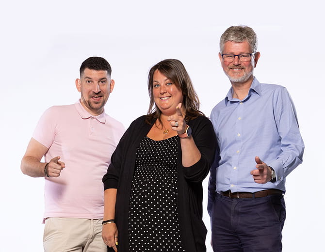 Three people standing in a group facing the camera with finger guns