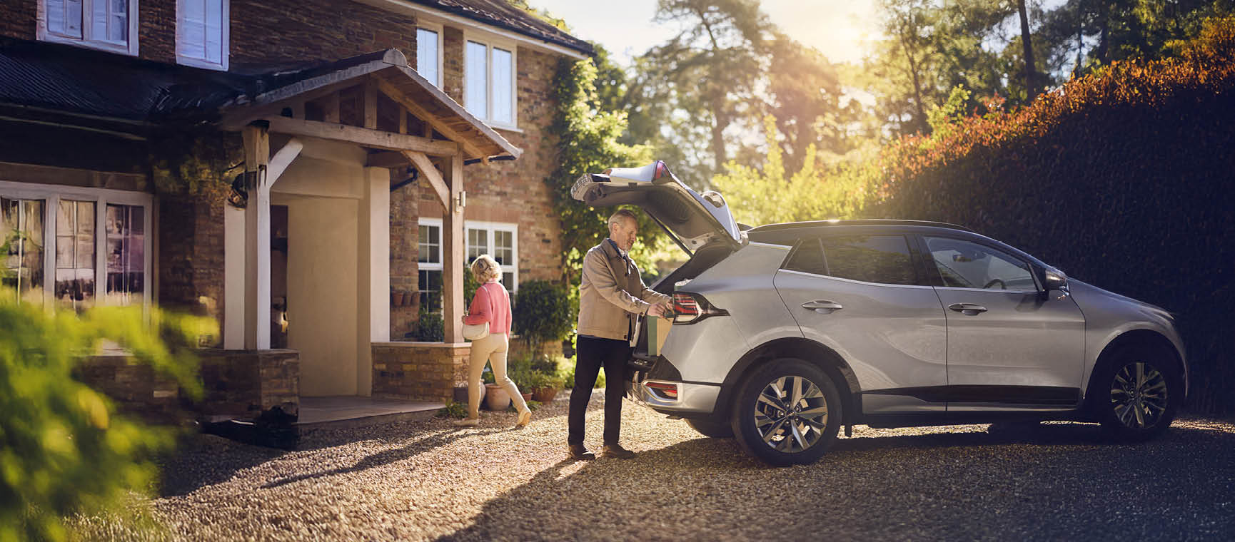 Person loading bags into the boot of a silver car outside a home, with another person walking toward the house and a Which? Best Buy logo.